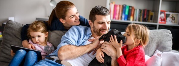 Família no sofá a brincar com o cão