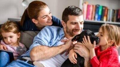 Família no sofá a brincar com o cão