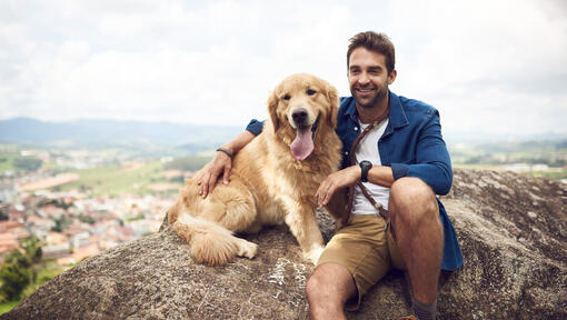 Homem com Golden Retriever na rocha