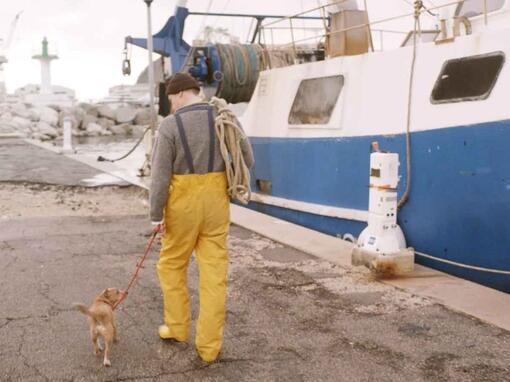 pescador passeando com seu cachorro ao lado do barco de pesca