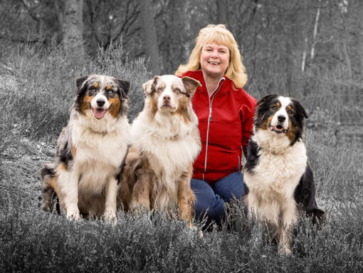 mulher com 3 cachorros sentados na grama