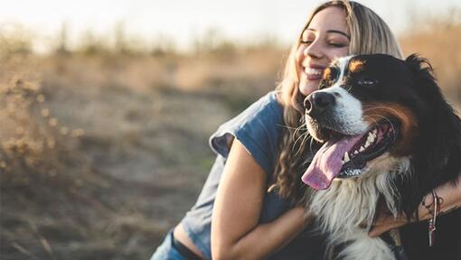 Uma mulher sorri e abraça um cão grande